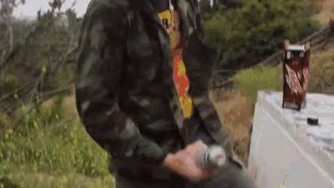 a man in a camouflage jacket is holding a can of soda
