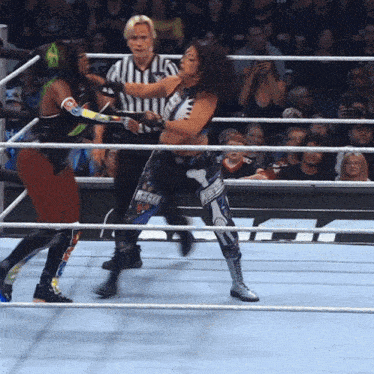 a woman in a wrestling ring with a referee behind her and the word rock on her outfit