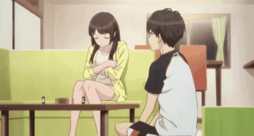 a man and a woman are sitting on a couch talking to each other .