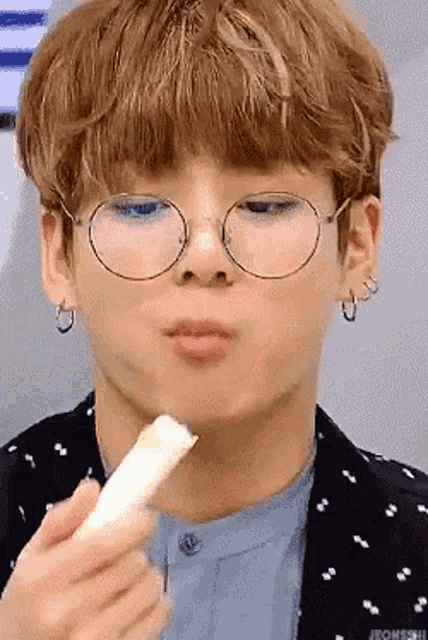 a close up of a person wearing glasses eating a piece of food .