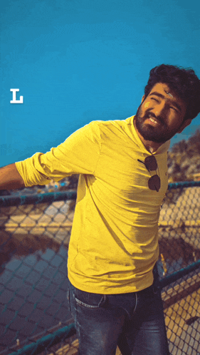 a man in a yellow shirt stands in front of a chain link fence with the letter i on the bottom