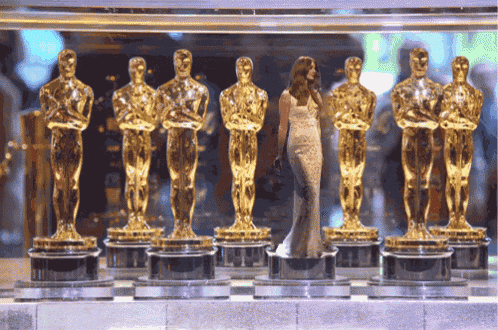a woman stands in front of a row of gold statues