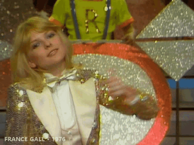 a woman in a sequined tuxedo is dancing with the year 1976 on the bottom left
