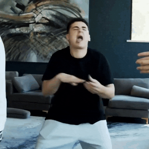 a man in a black shirt and white shorts is dancing in a living room