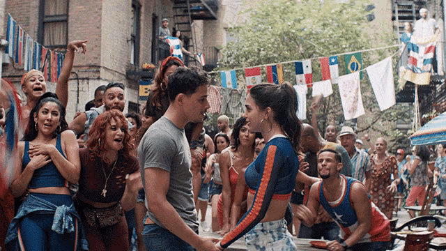 a group of people are dancing in a street with flags hanging from a clothes line