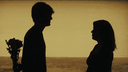 a man is holding a bouquet of flowers behind his back and a woman is looking at him
