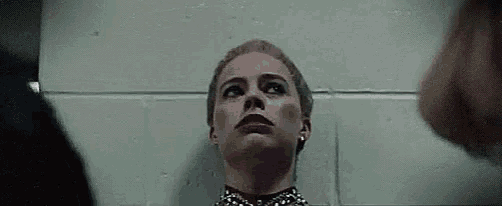 a woman is standing in front of a wall and looking up at the sky .