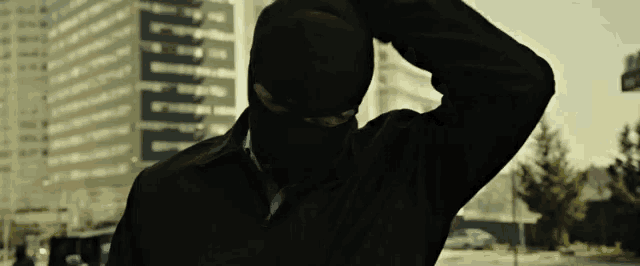 a man wearing a black mask is standing in front of a building