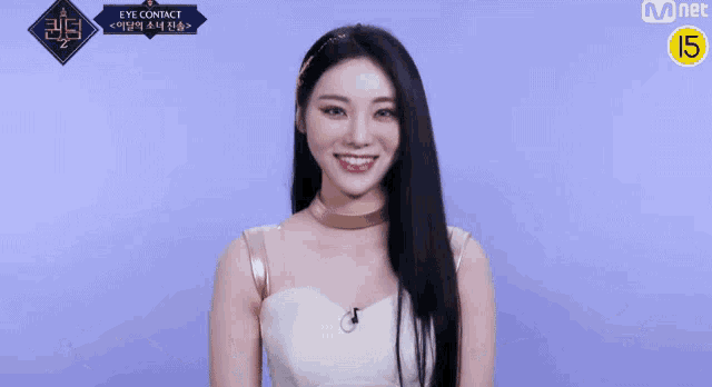 a woman with long black hair is wearing a white top and a gold choker .