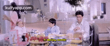 a family is sitting at a table eating food and drinking tea .
