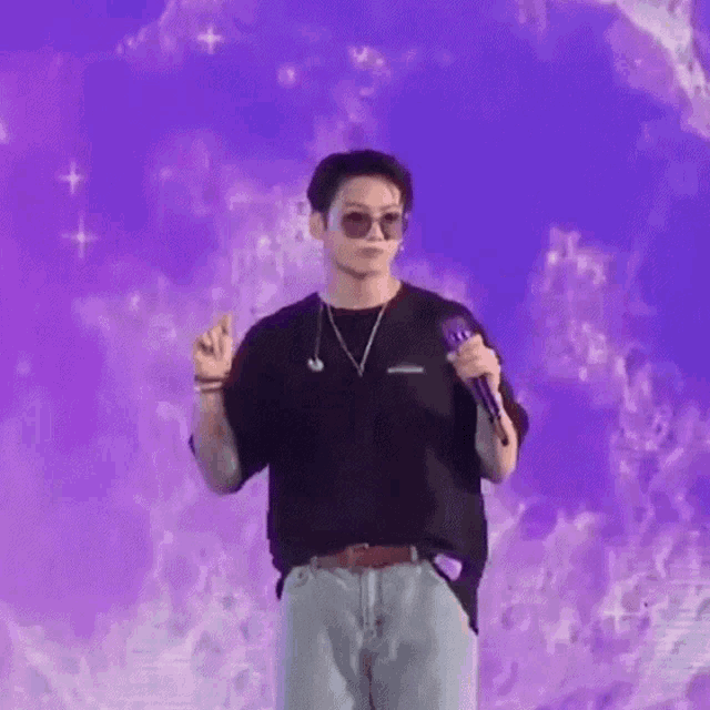 a man is standing on a stage holding a microphone in front of a purple wall .