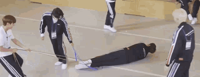 a group of people are playing a game of tug of war on a gym floor .