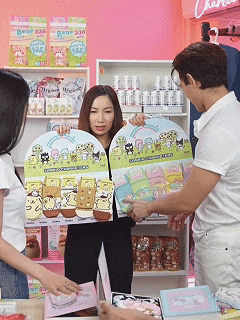 a man and two women are looking at a display of pom pom socks in a store