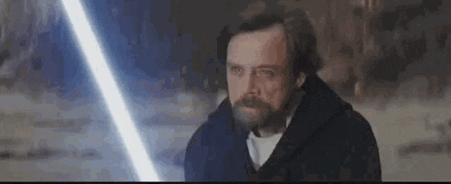 a man with a beard is holding a light saber in his hands .