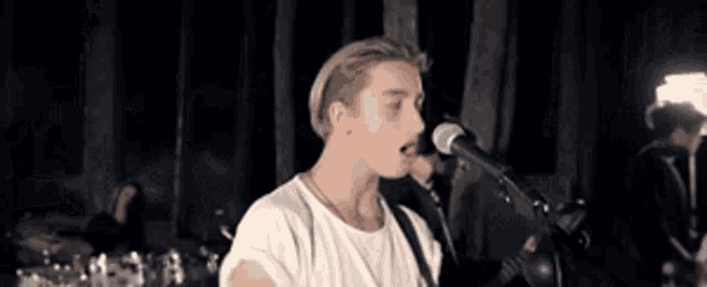 a man singing into a microphone while playing a guitar .