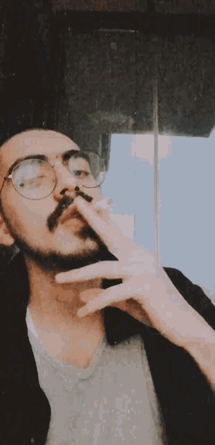 a man with glasses and a beard is smoking