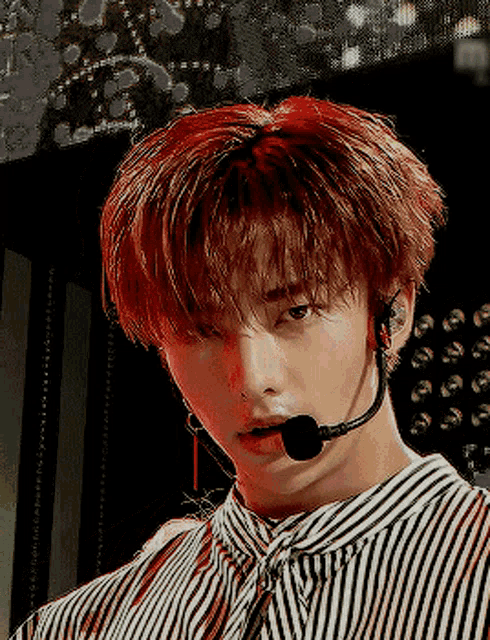 a young man wearing a striped shirt and a microphone