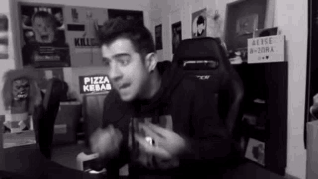 a man is sitting in a chair in a room with a sign that says pizza kebab .