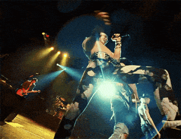 a man singing into a microphone on a stage with a band behind him