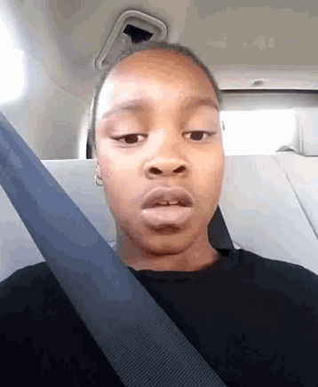a young girl is wearing a seat belt and making a funny face