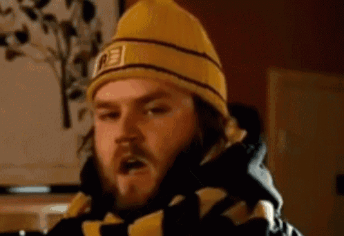 a man with a beard wearing a yellow beanie and a scarf .