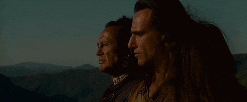 two men and a woman are standing next to each other in front of mountains