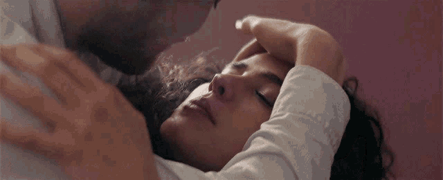 a man kissing a woman on the forehead while laying down