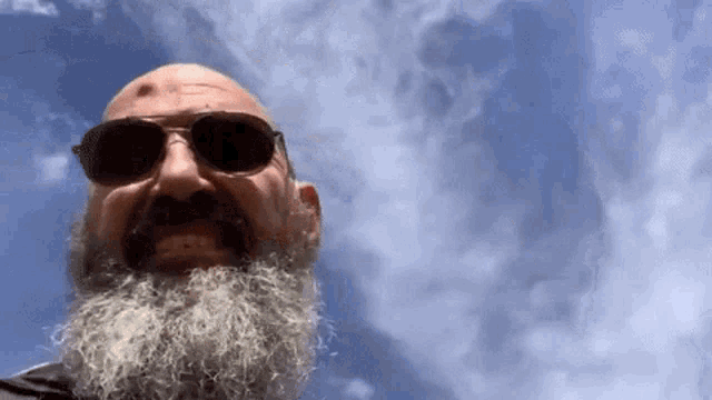 a man with a beard is wearing sunglasses and looking at the camera