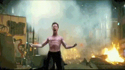 a man without a shirt is standing in front of a fire and smoke .