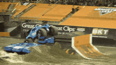 a monster truck is going over a ramp in front of a bkt advertisement