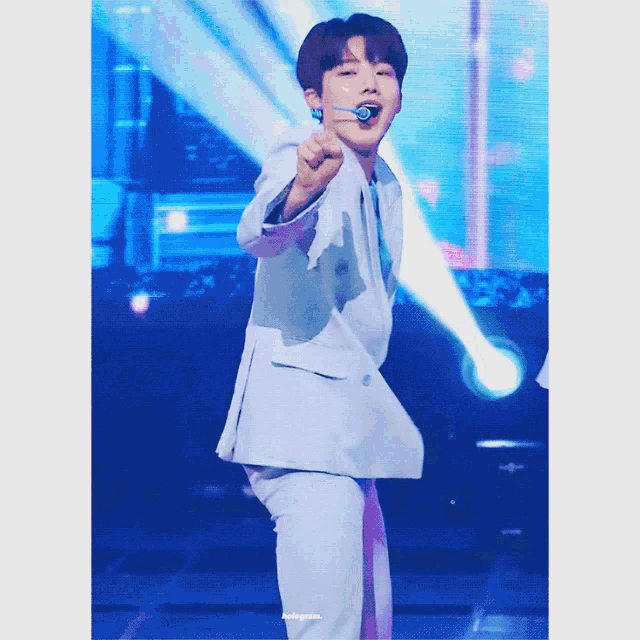 a man in a white suit is dancing on a stage with a microphone in his mouth
