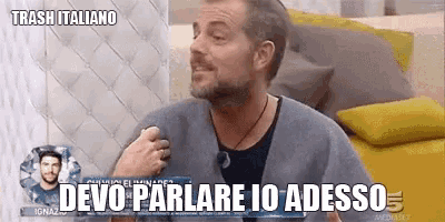 a man is sitting on a couch with a sign that says devo parlare io adesso