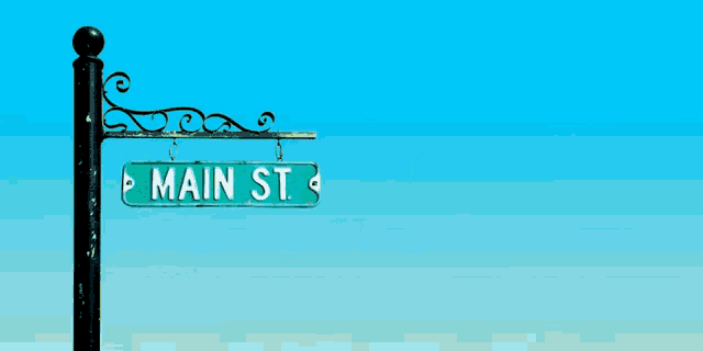 a street sign for main st. has a blue sky in the background