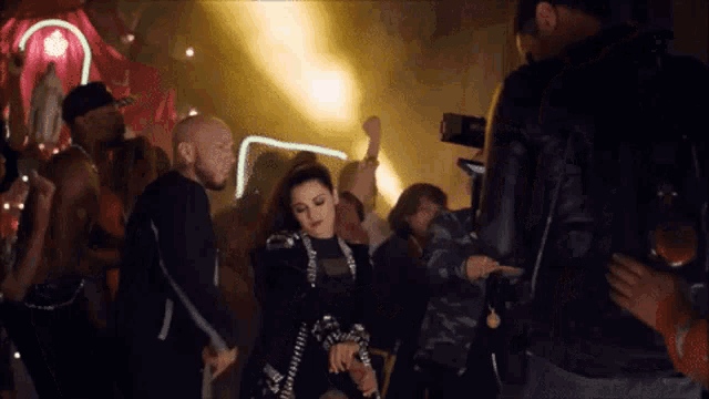 a group of people are dancing at a party and one of them is wearing a black jacket that says supreme