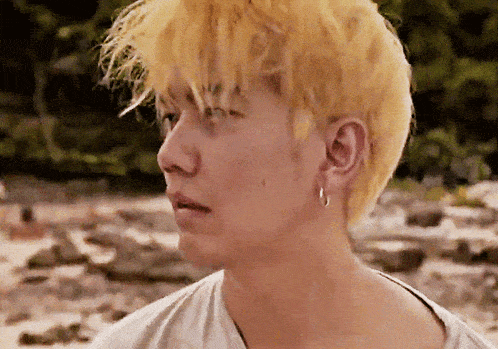 a close up of a man 's face with yellow hair and hoop earrings