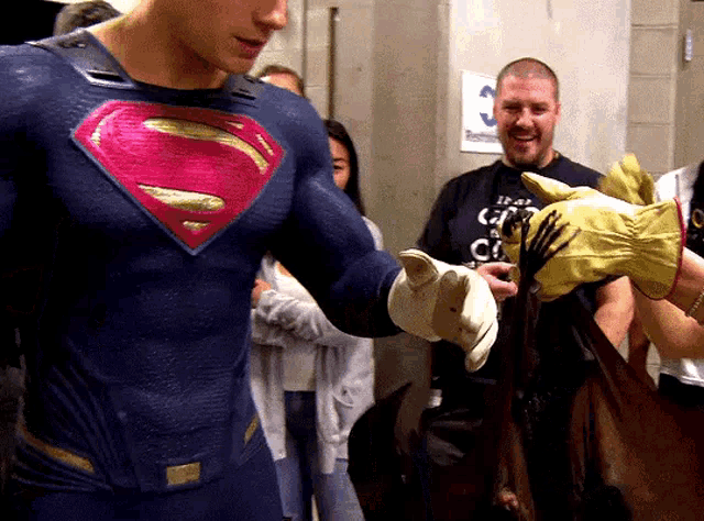 a man in a superman suit holds a pair of gloves