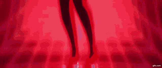 a woman in a red dress is standing in front of a red background with glowing lights .