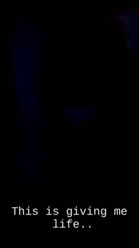 a woman sitting in a dark room with the words " this is giving me life " on the bottom