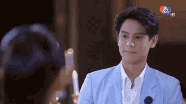 a man in a blue suit and white shirt is looking at a woman in a room .