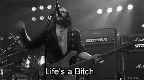 a man playing a guitar and singing into a microphone with the words life 's a bitch above him