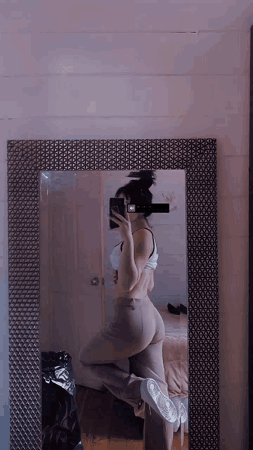 a woman taking a selfie in front of a mirror with a purple background