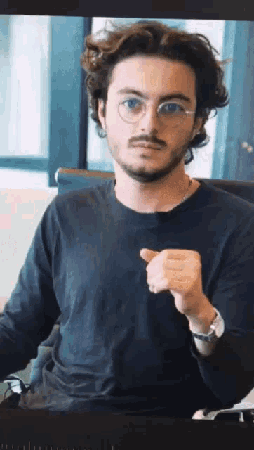 a man with glasses and a beard is pointing