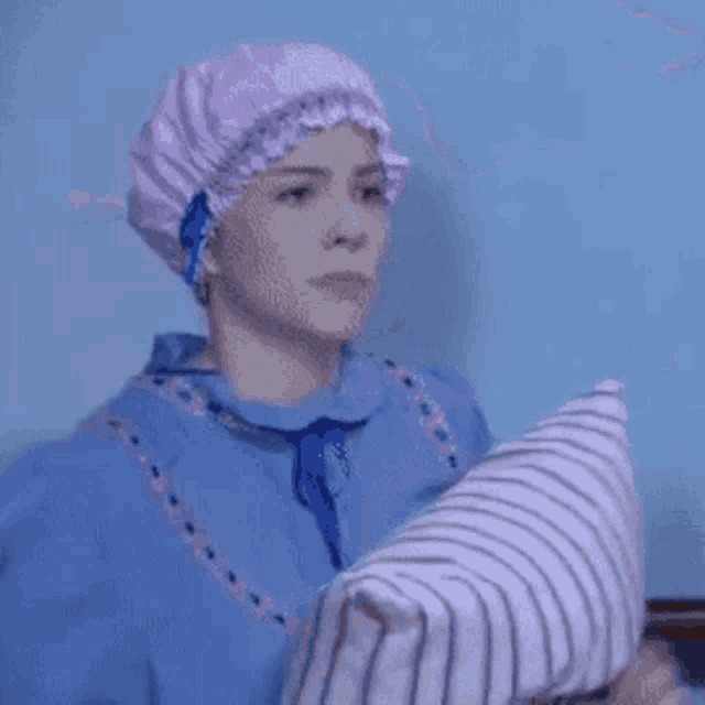 a woman wearing a purple surgical cap and blue scrubs is holding a person 's arm