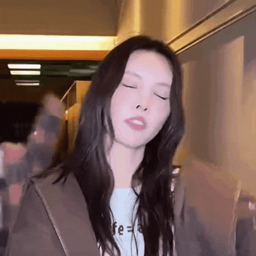 a woman with long dark hair is wearing a jacket and a white shirt .