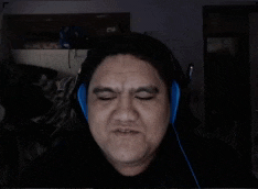 a man wearing blue headphones is smiling in a dark room