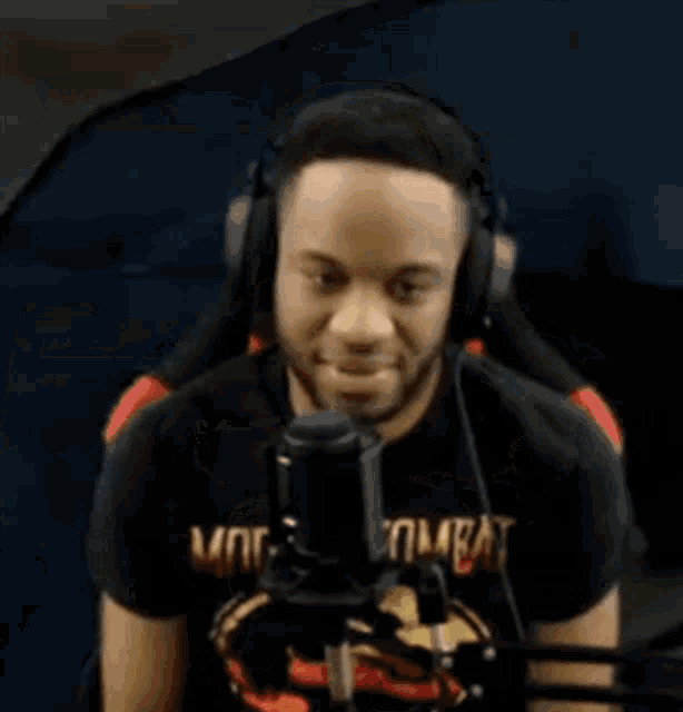 a man wearing headphones is sitting in front of a microphone and says oh fuck .