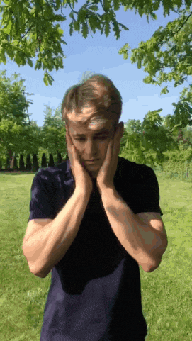 a man in a black shirt is covering his ears in a park