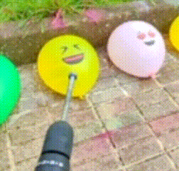 a yellow balloon with a face on it is being drilled with a drill