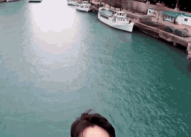 a person taking a selfie in front of a body of water with boats in it