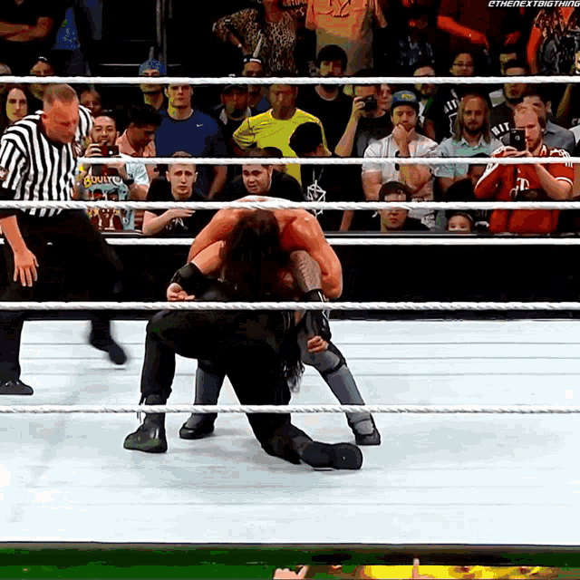 a wrestling match between roman reigns and a referee with the next thing written in the corner